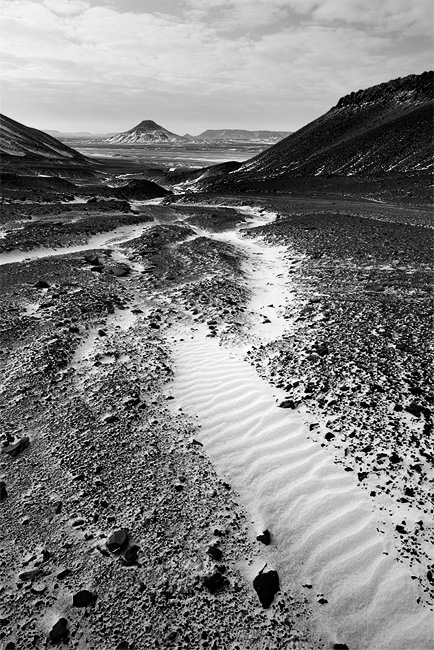  Fotografie Egypt, Černá poušť - Krajina Černé pouště (Black Desert) a v pozadí jeden z kuželovitých kopců.